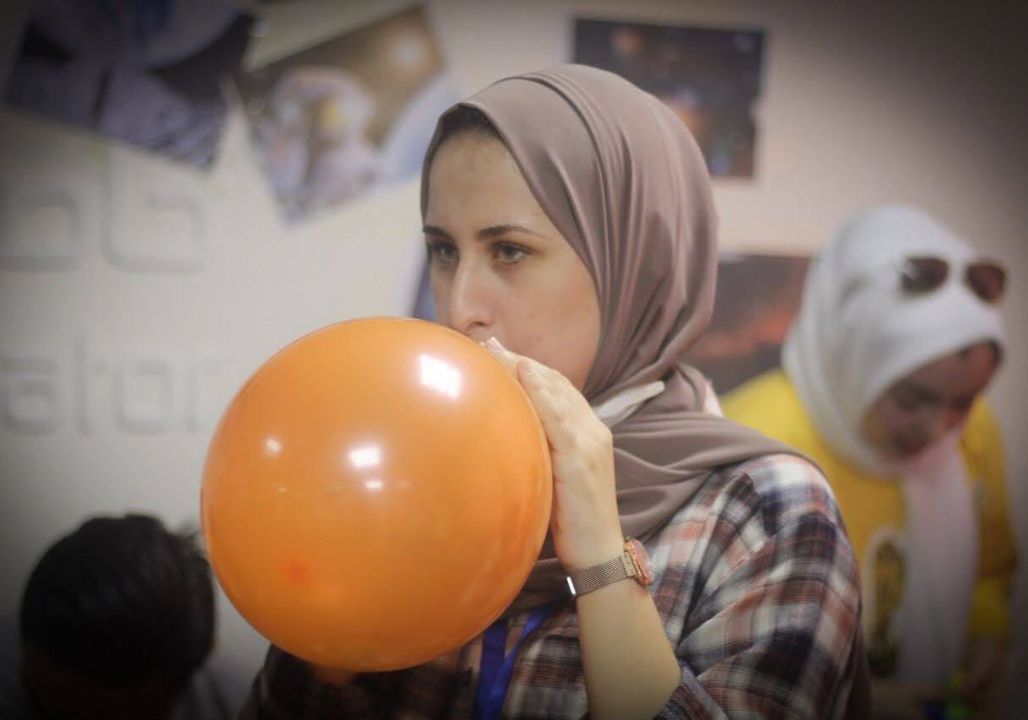 Saja Redwan blowing up a balloon during an astronomy mentorship programme for children.