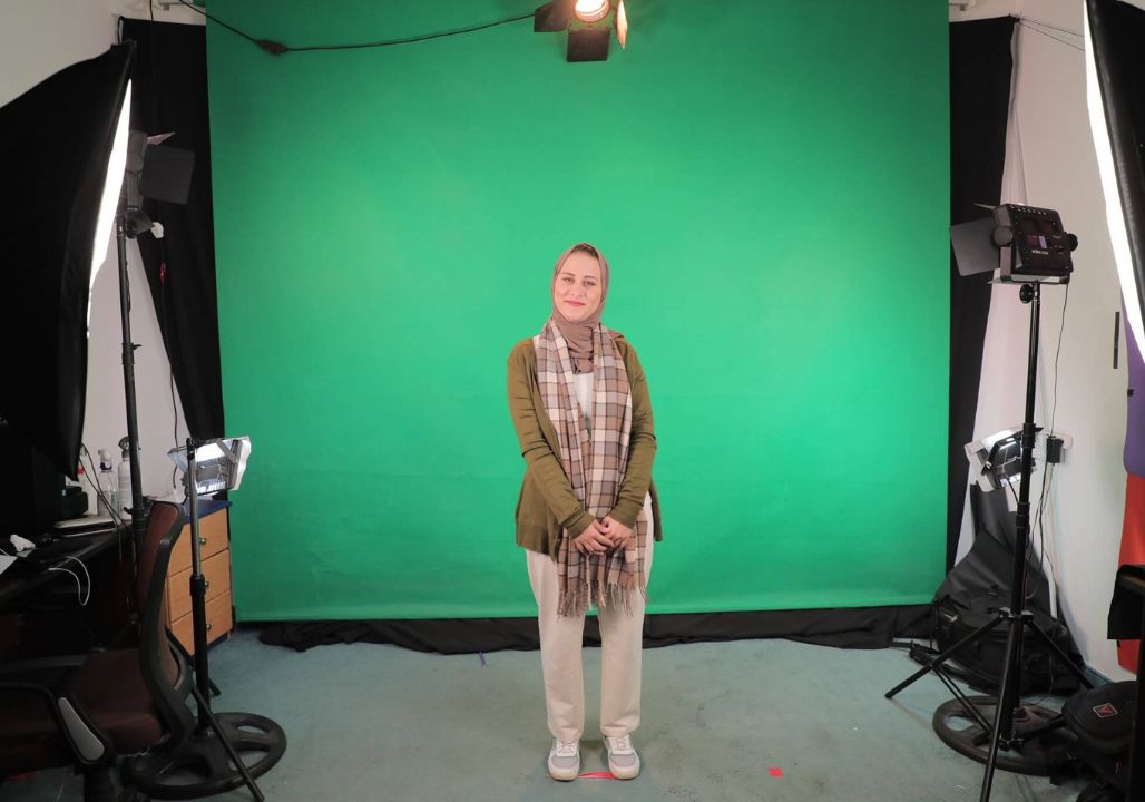 Saja Redwan posing in front of a green screen as part of a behind-the-scenes photo of her TV presenting work.